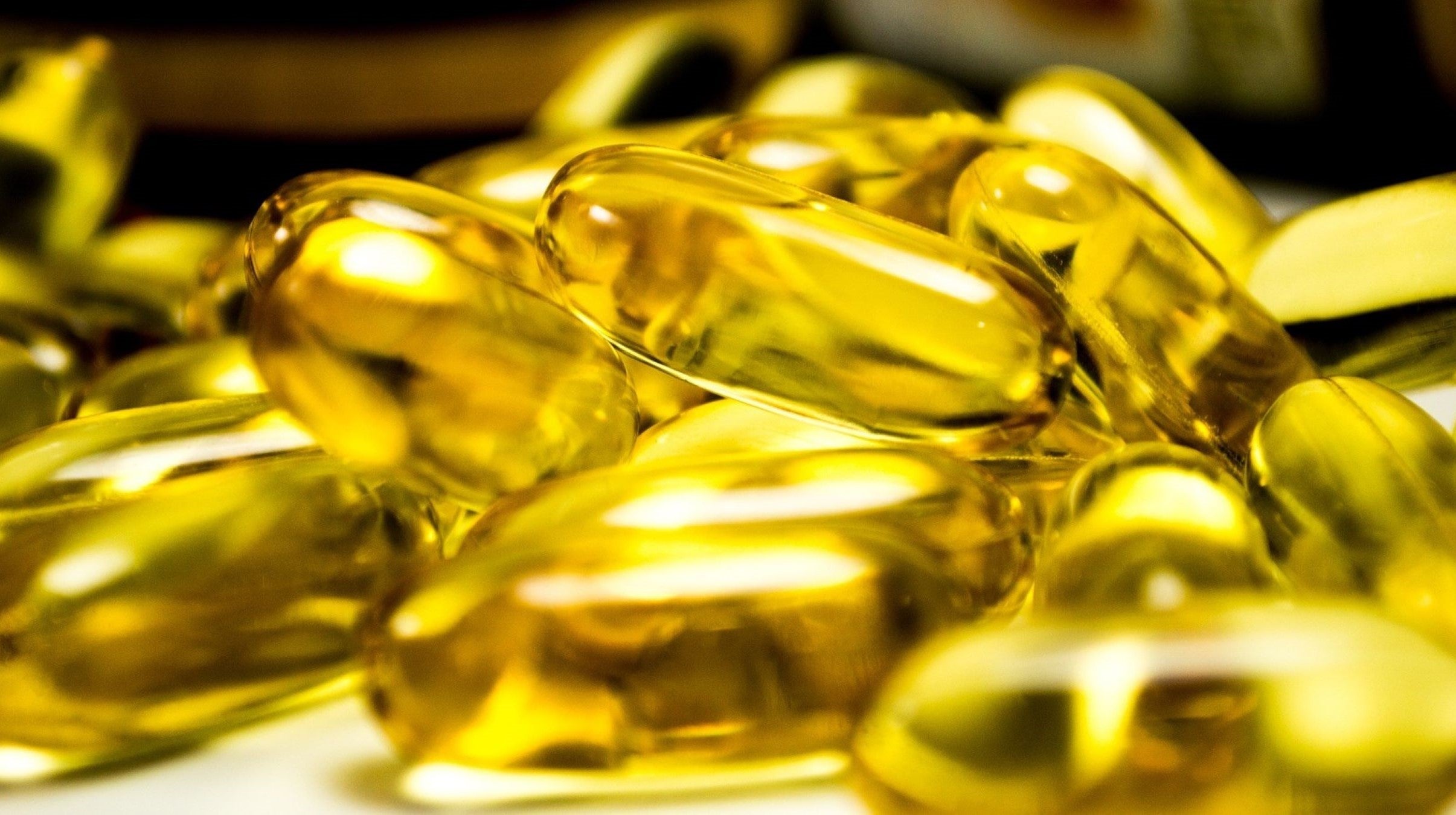 Pile of dietary supplement capsules containing golden liquid omega 3