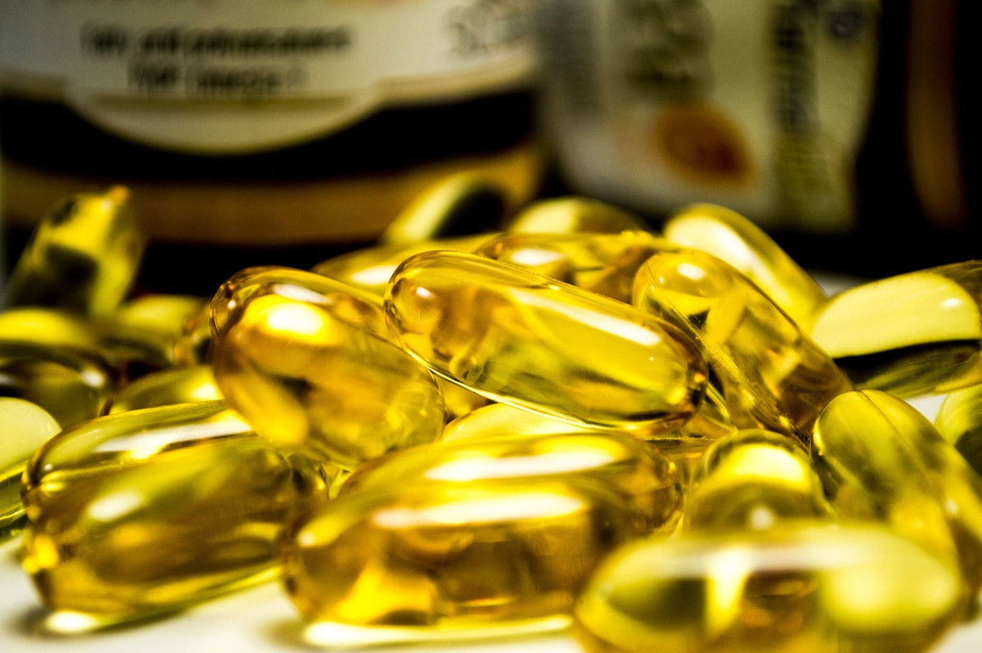 Pile of clear amber dietary supplement capsules containing omega oils and vitamins 